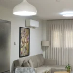 Καθιστικό με γωνιακό καναπέ, κρεμαστό φωτιστικό και διακοσμητικό πίνακα με λουλούδια