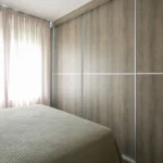 Υπνοδωμάτιο με ξύλινη ντουλάπα-τοίχο και απαλό φυσικό φως από το παράθυρο