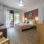 Studio με καναπέ, διπλό κρεβάτι και τοίχο σε χρώμα τερακότα, με έξοδο στο μπαλκόνι